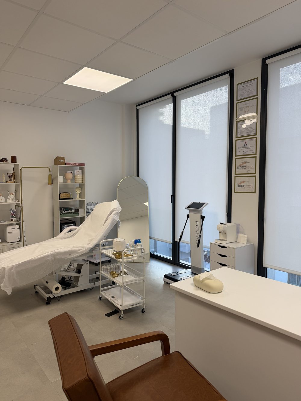 Une cabine de soins avec sa table de soin et les diplômes du médecin encadrés
